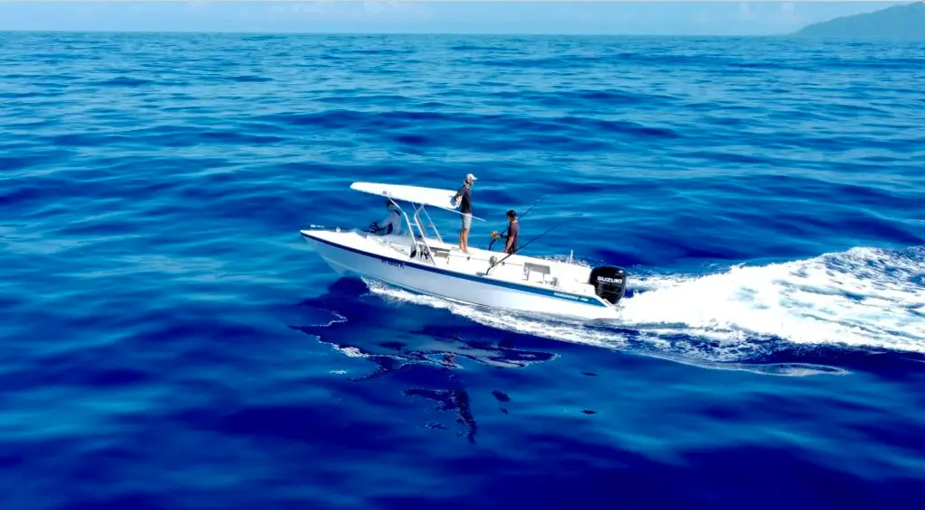 Vue aérienne d'un bateau de pêche de Tahiti Ocean Adventure naviguant sur les eaux cristallines et bleues de Tahiti, illustrant l'expertise et l'équipement moderne utilisé pour les sorties de pêche au gros à Tahiti dans cette région paradisiaque.